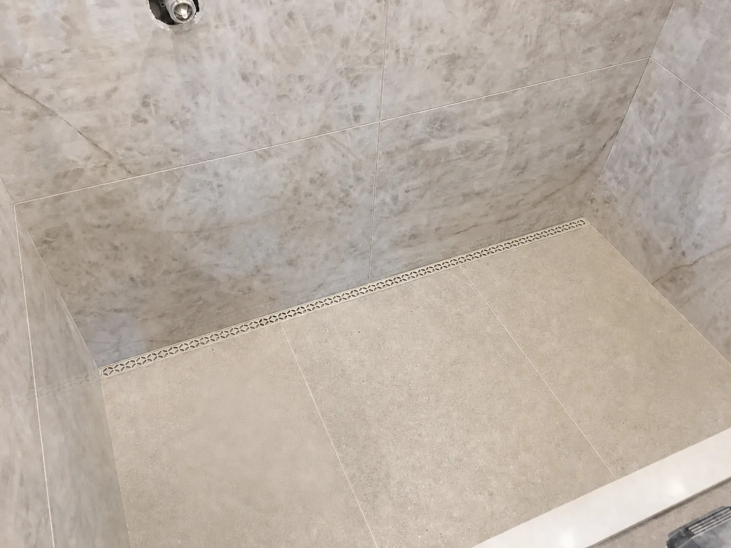 Large-format shower tile carefully aligned with a linear drain